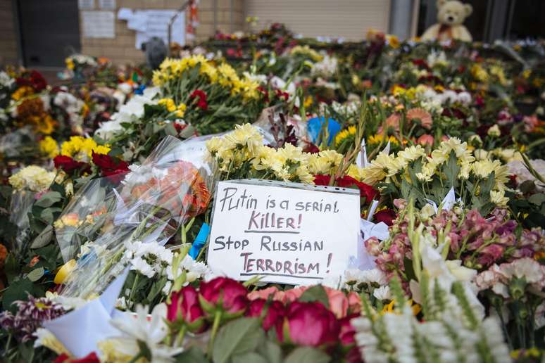 Cartaz que diz "Putin é um assassino em série" e "parem o terrorismo russo" é colocado em meio a flores na embaixada holandesa em Kiev, Ucrânia, em homenagem às vítimas do voo da Malaysia Airlines