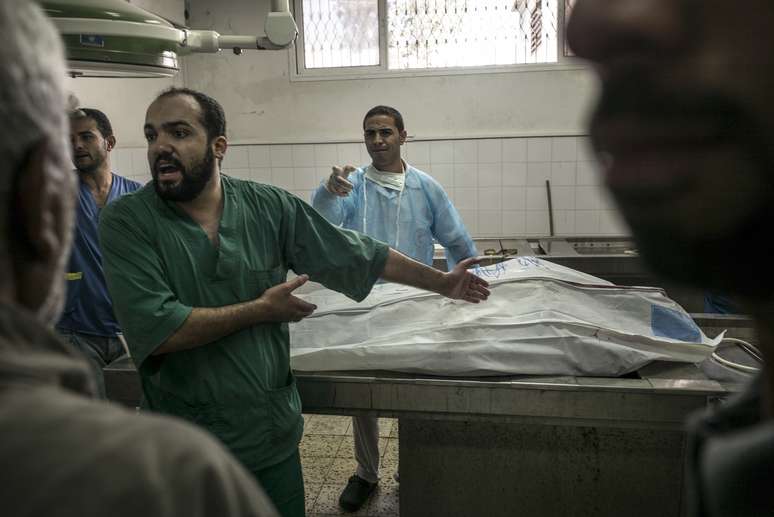 <p>Um médico reage ao lado de um corpo no necrotério do hospital al-Shifa, na Cidade de Gaza, nesta segunda-feira, 20 de julho, na sequência de bombardeio pelo exército israelense no enclave palestino</p>