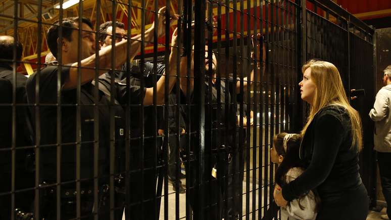 <p>Mulher e criança corintianas tentam argumentar com seguranças do metrô em portão fechado após jogo do Corinthians em Itaquera</p>