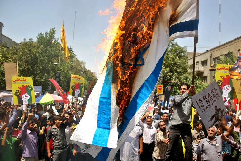 <p>Manifestantes queimam uma bandeira de Israel durante os protestos de 25 de julho</p>