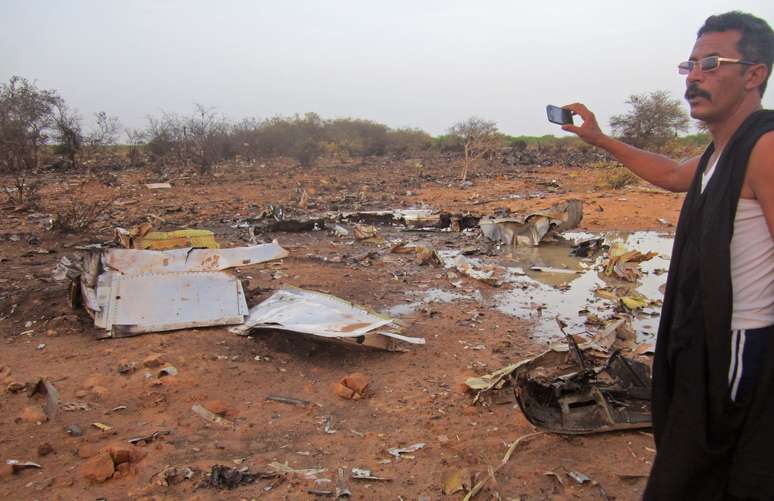 <p>Um homem tira foto dos detroços do avião que caiu no Mali com 118 pessoas a bordo</p>