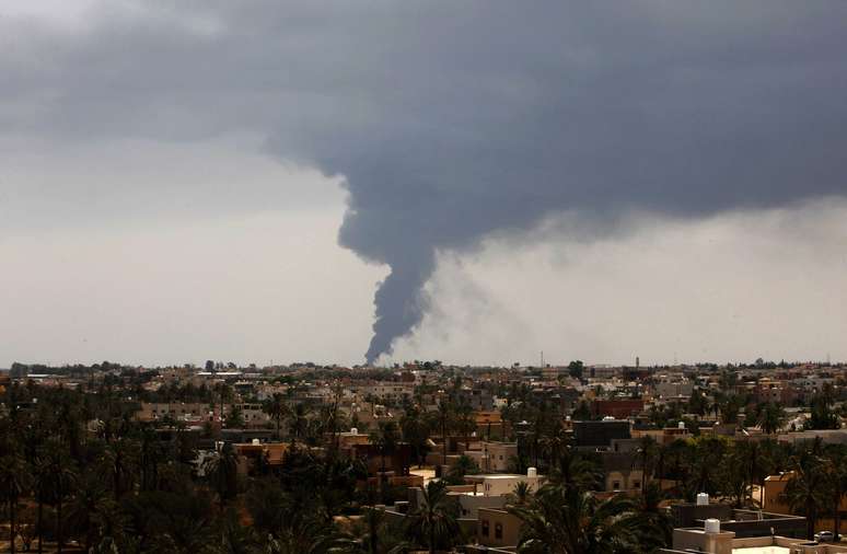 <p>Nuvens de fumaça sobem do local onde um foguete atingiu um tanque de armazenamento de combustível perto da estrada do aeroporto de Trípoli, durante confrontos entre milícias rivais, em 28 de julho</p><p> </p>
