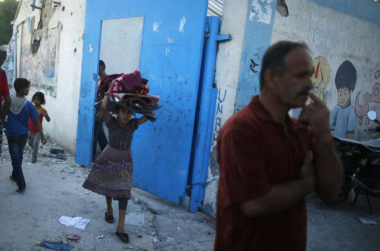 <p>Uma menina palestina carrega seus pertences enquanto deixa uma escola das Na&ccedil;&otilde;es Unidas atingida&nbsp;por um bombardeio israelense, em 30 de julho</p>