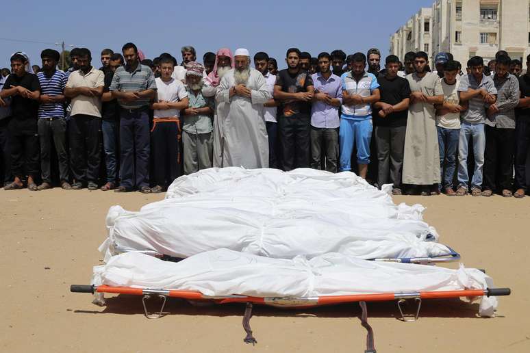 <p>Pessoas rezam ao lado de corpos de palestinos mortos em um ataque aéreo israelense no sul da Faixa de Gaza, em 30 de julho</p>