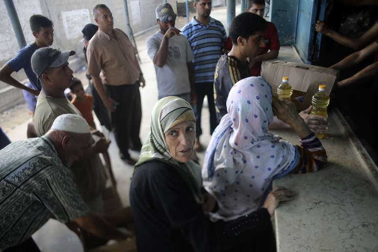 <p>Palestinos esperam para receber alimentos em um centro de distribuição de alimentos das Nações Unidas em Khan Younis, no sul da Faixa de Gaza, nesta quinta-feira, 31 de julho</p>