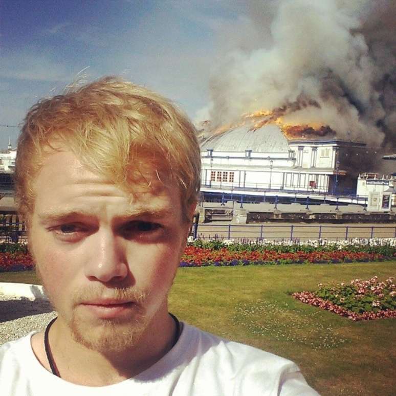 Mas antes... Deixa-me tirar uma selfie, disse o rapaz na imagem ao lado do incêndio