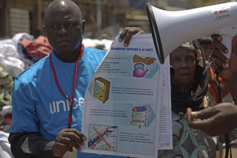 <p>Um trabalhador UNICEF segura&nbsp;um cartaz com informa&ccedil;&otilde;es para evitar o ebola em Conacri, capital da Guin&eacute;</p><p>&nbsp;</p>