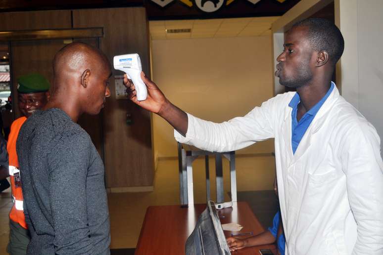 <p>Agente de saúde verifica um passageiro no aeroporto de Conacri, Guiné, em 22 de julho de 2014. Acessórios de proteção e material de saúde são adotados por funcionários do aeroporto contra a propagação do vírus Ebola</p>