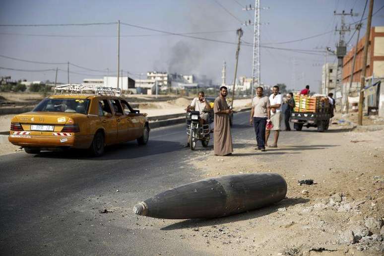 <p>Palestinos observam proj&eacute;til lan&ccedil;ado de Israel que n&atilde;o explodiu na cidade de Deir Al-Balah, na Faixa de Gaza</p>