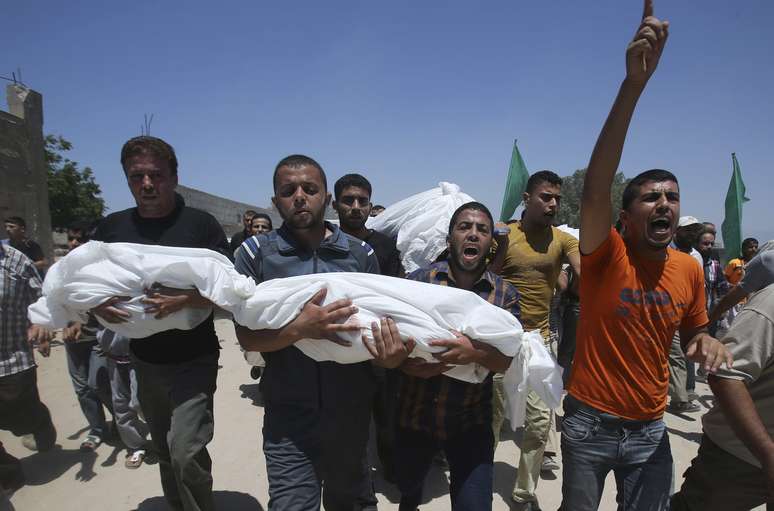 <p>Palestinos carregam os corpos de crian&ccedil;as mortas durante ataques israelenses no sul da Faixa de Gaza, em 29 de julho</p>