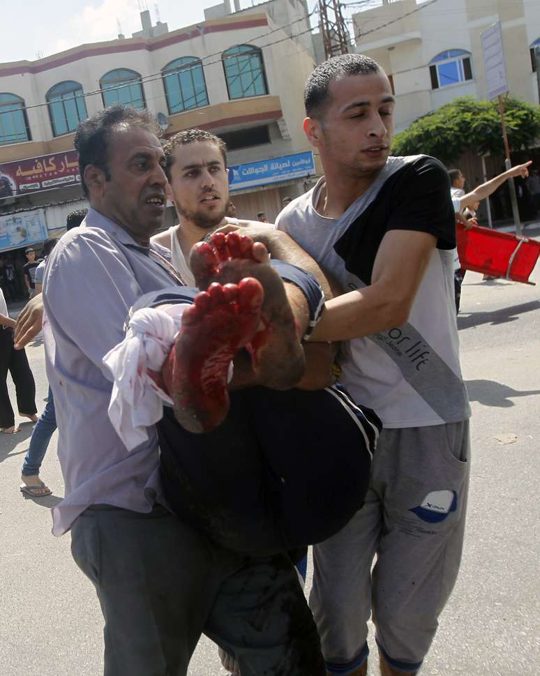 <p>Palestinos carregam um homem ferido após o ataque israelense contra uma escola da ONU, em Rafah, no sul da Faixa de Gaza, em 3 de agosto</p>