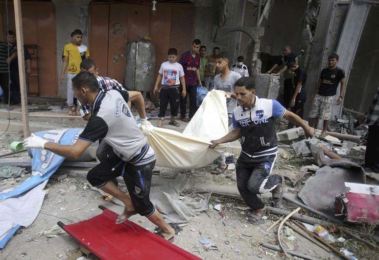 <p>Palestinos carregam o corpo de uma mulher retirado dos escombros de uma casa que segundo testemunhas foi destruída em um bombardeio de Israel, na Faixa de Gaza</p>