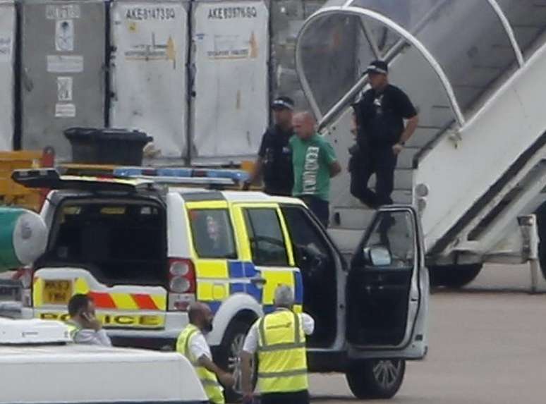 <p>Um homem é escoltado pela polícia para fora do avião da Qatar Airways, no aeroporto de Manchester, norte da Inglaterra, nesta terça-feira, 5 de agosto</p>
