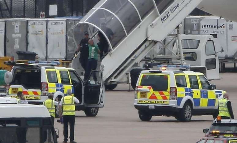 Homem é retirado pela polícia de um avião da Qatar Airways no aeroporto de Manchester, na Inglaterra. 5/08/2014.