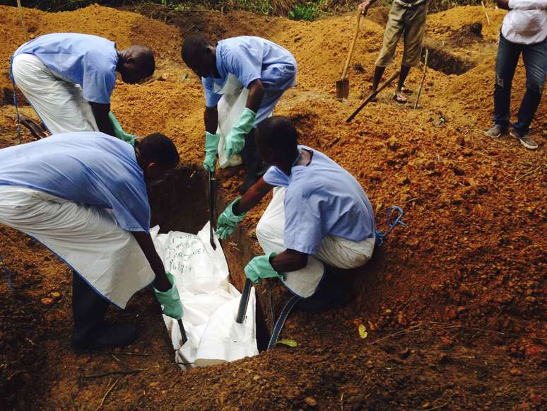 <p>Volunt&aacute;rios enterram o corpo de uma pessoa infectada pelo&nbsp;v&iacute;rus Ebola, em uma sepultura em Kailahun, em&nbsp;2 de agosto</p>