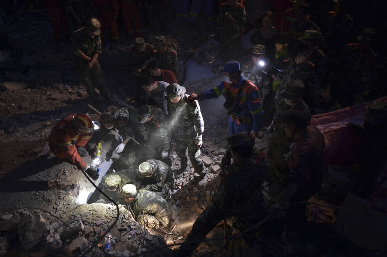 <p>Policiais paramilitares procuram o corpo de um menino enterrado sob os escombros, após o terremoto que atingiu a comarca de Ludian, na província de Yunnan, em 05 de agosto</p>