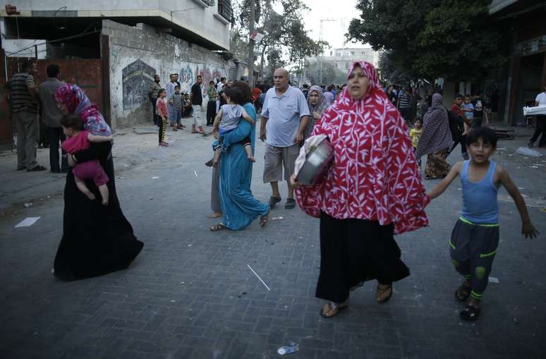 Palestinos carregam alguns pertences enquanto deixam suas casas em Gaza, ap&oacute;s fim de tr&eacute;gua