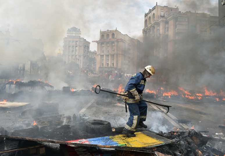 <p>Um bombeiro extingue um inc&ecirc;ndio causado pela queima de uma barricada na Pra&ccedil;a da Independ&ecirc;ncia, em Kiev,&nbsp;durante confrontos de residentes da capital ucraniana, neste s&aacute;bado, 9 de agosto</p>