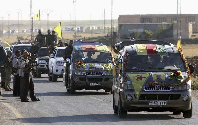 Combatentes curdos em comboio com caixões de outros combatentes mortos em confrontos com o Estado Islâmico na cidade iraquiana de Rabia, na fronteira Síria-Iraque. 06/08/2014
