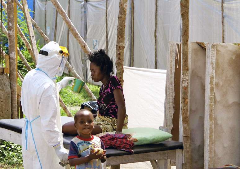 <p>Paciente com ebola é alimentada por um agente de saúde em Serra Leoa</p>