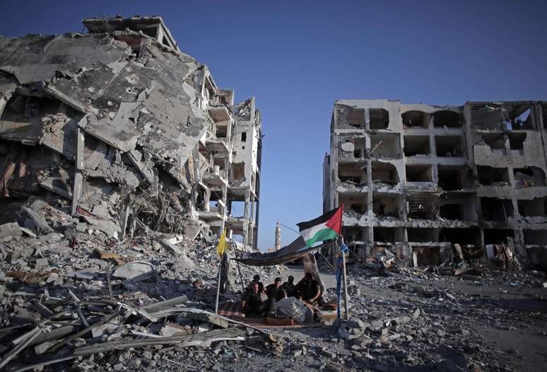 <p>Palestinos que perderam suas casas e seus estabelecimentos durante a ofensiva israelense sentam-se em um abrigo improvisado na cidade de Beit Lahiya, norte da Faixa de Gaza, em 11 de agosto</p>