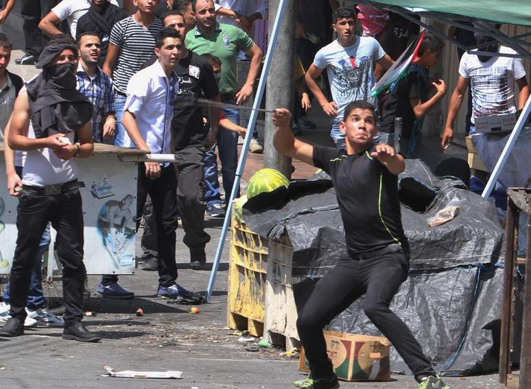 <p>Manifestantes palestinos atiram pedras em soldados israelenses durante&nbsp;um protesto contra a a&ccedil;&atilde;o militar israelense em Gaza, na cidade de Hebron, em 15 de agosto</p>