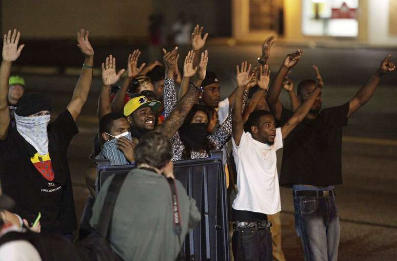 Manifestantes levantam as mãos durante protestos contra a morte de Michael Brown, que pode ter morrido com até seis tiros lançados por um policial