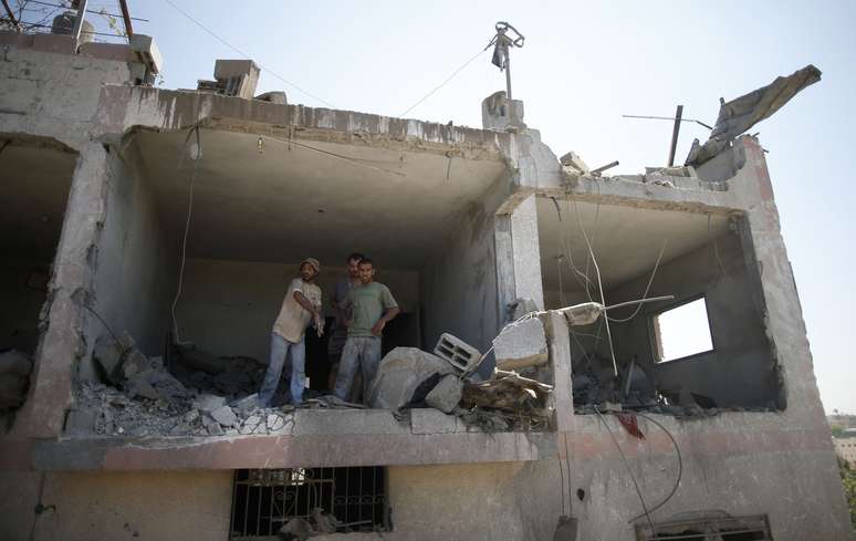 <p>Palestinos observam destro&ccedil;os de uma casa vizinha atingida por um ataque a&eacute;reo isralense em Beit Lahiya, no norte da Faixa de Gaza, em 25 de agosto</p>