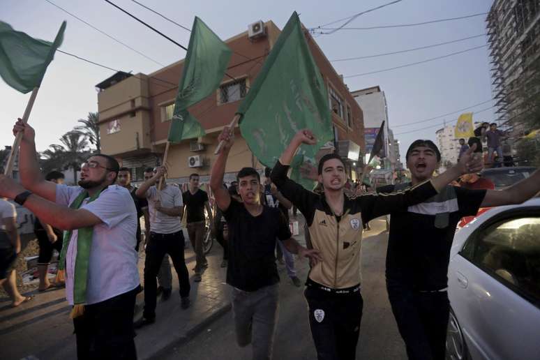 <p>Palestinos brandem&nbsp;bandeiras nacionais durante celebra&ccedil;&atilde;o do acordo de cessar-fogo entre Israel e Hamas&nbsp;na principal rua da Cidade de Gaza</p>