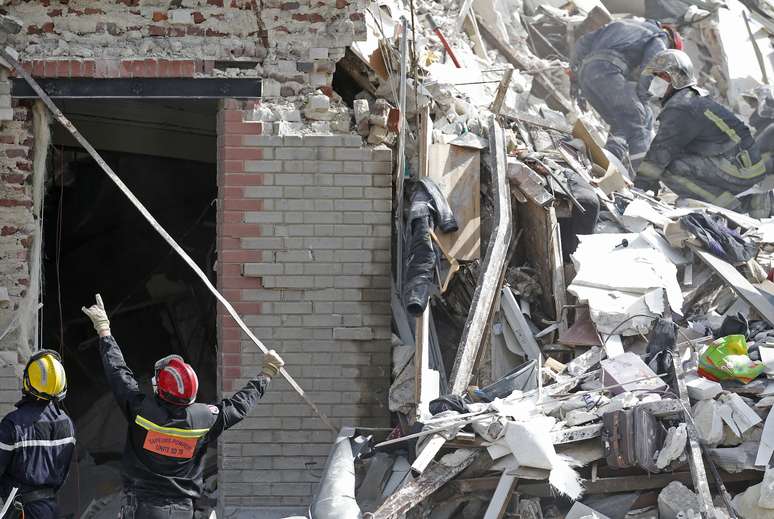 Bombeiros trabalham em escombros procurando desaparecidos após explosão