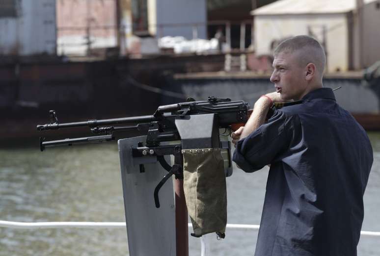 Soldado ucraniano fica ao lado de arma no porto de Mariupol