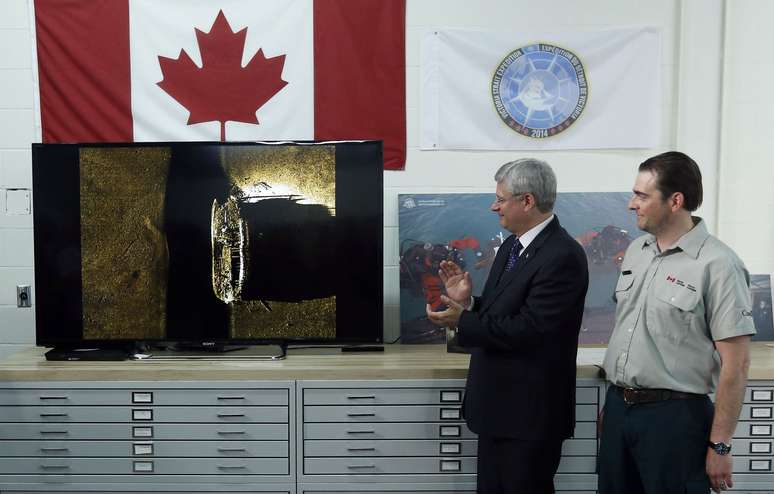 Primeiro-ministro do canadá, Stephen Harper (à esquerda) aplaude após ser apresentado às imagens dos destroços encontrados