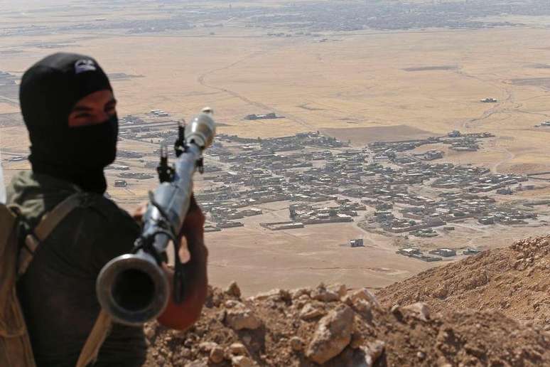 Combatente  curdo peshmerga com lançador de granada apontado para o vilarejo de Baretle, que é controlado pelo Estado Islâmico, no Iraque.
