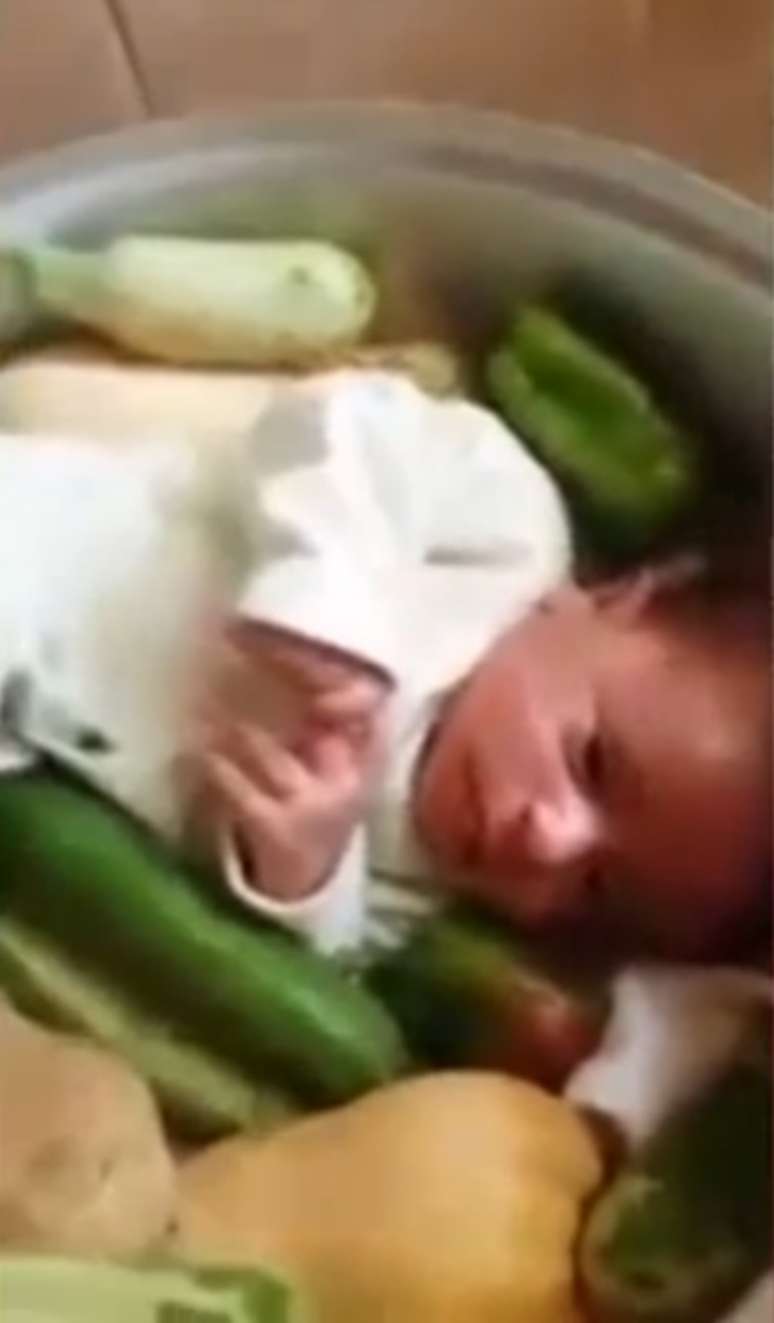 <p>Quando o pai da criança abre a panela, um bebê é visto ao lado de legumes</p>