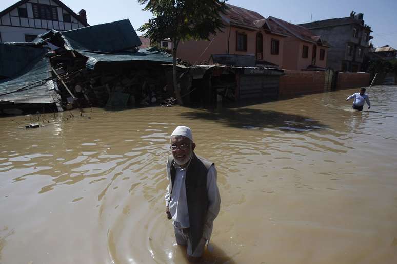 Cidadãos da Caxemira caminham em meio a água e casas danificadas, em uma rua inundada, em Srinagar , em 14 de setembro