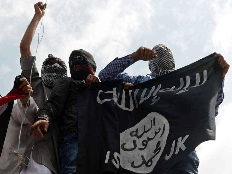 <p>Militantes do Estado Islâmico exibem bandeira do grupo jihadista</p>