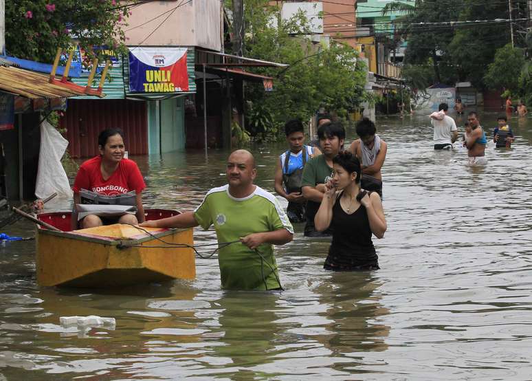 <p>Moradores usam um pequeno barco para o transporte de uma mulher por uma rua inundada após a tempestade tropical Fung-Wong, na província de Rizal, a leste de Manila, em 20 de setembro</p>