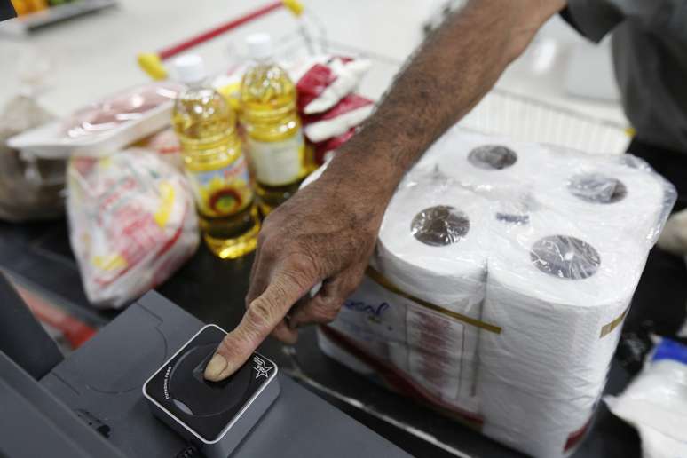 Cliente coloca o dedo sobre um leitor de digitais, para compra de mercadorias no Bicentenário, um supermercado estatal, em Caracas