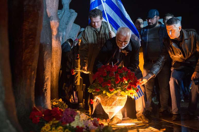 <p>Manifestante coloca flores em frente ao monumento&nbsp;Trag&eacute;dia dos povos</p>