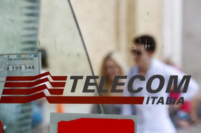 Pessoas passam atrás de um logotipo da Telecom Italia em Roma.