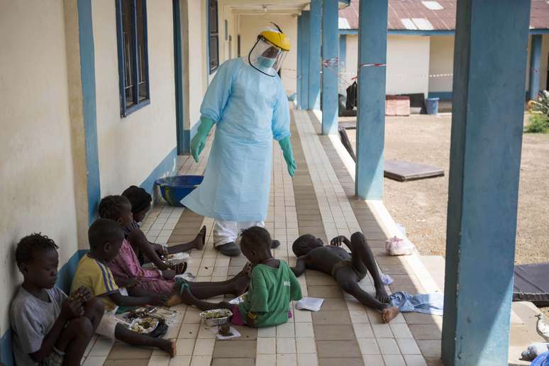 <p>Um agente&nbsp;de sa&uacute;de vestido&nbsp;com equipamentos de prote&ccedil;&atilde;o examina&nbsp;crian&ccedil;as v&iacute;timas do&nbsp;ebola em um centro de&nbsp;Makeni, em&nbsp;Serra Leoa, em 4 de outubro</p>