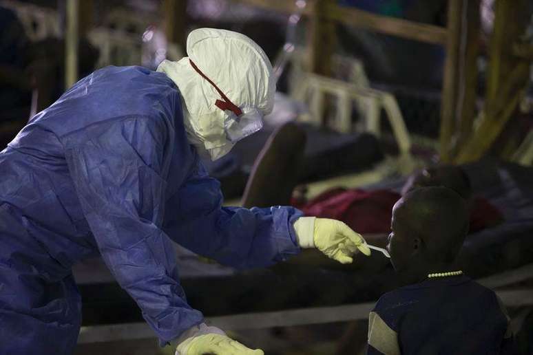 <p>Funcionário de saúde usando equipamento de proteção presta atendimento a um paciente tratado por ebola em Monróvia, na Libéria</p>