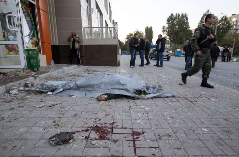 <p>Um policial caminha próximo ao corpo de uma vítima, morta em um bombardeio em Donetsk, na Ucrânia, em 8 de outubro</p>