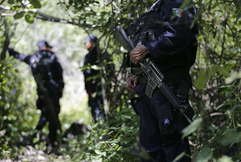 <p>Policiais montam guarda em uma &aacute;rea perto das fossas clandestinas em Pueblo Viejo, na periferia de Iguala, no estado mexicano de Guerrero, em 9 de outubro</p>