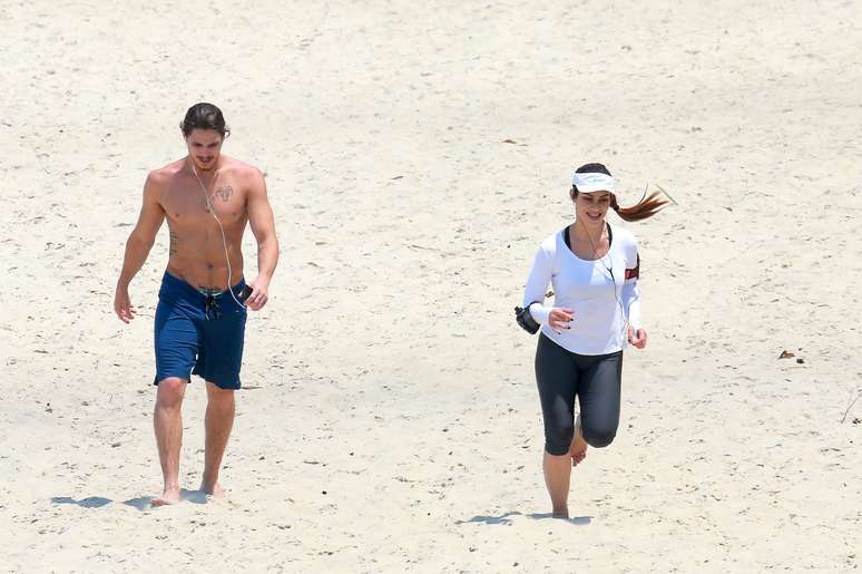 Cléo Pires e Rômulo Neto caminham na praia