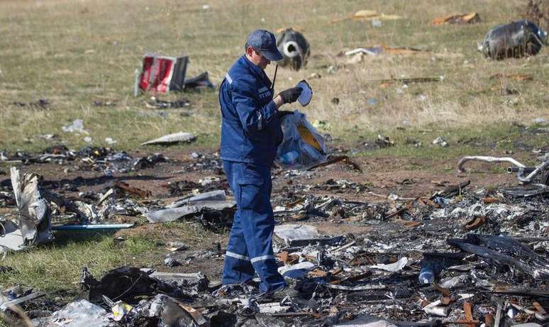 <p>Membro do Minist&eacute;rio da Emerg&ecirc;ncia busca por pertences de passageiros mortos no local em que caiu o voo MH17</p>