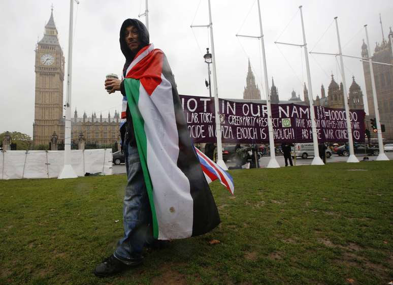 <p>Um homem coberto por&nbsp;uma bandeira palestina caminha pr&oacute;ximo ao Parlamento em Londres, em 13 de outubro</p><p>&nbsp;</p>