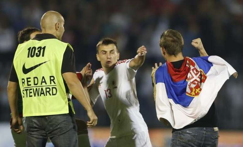 Burim Kukeli, da seleção da Albânia, e um colega de time brigam com um torcedor da Sérvia durante partida entre as seleções dos dois países pelas eliminatórias da Eurocopa de 2016. 14/10/2014.