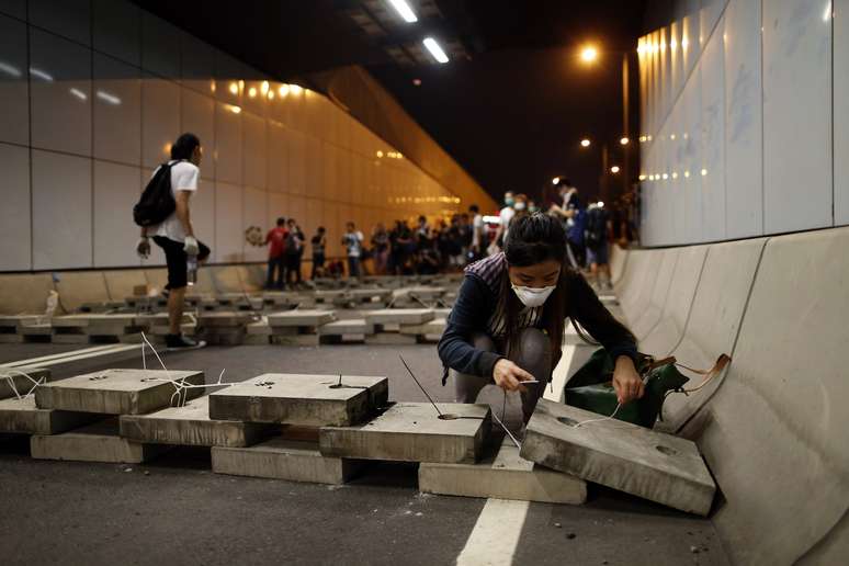 <p>Um manifestante pró-democracia deposita tijolos dentro de um túnel para bloquear o tráfego que conduz ao distrito financeiro central, perto da sede do governo em Hong Kong, em 14 de outubro </p>