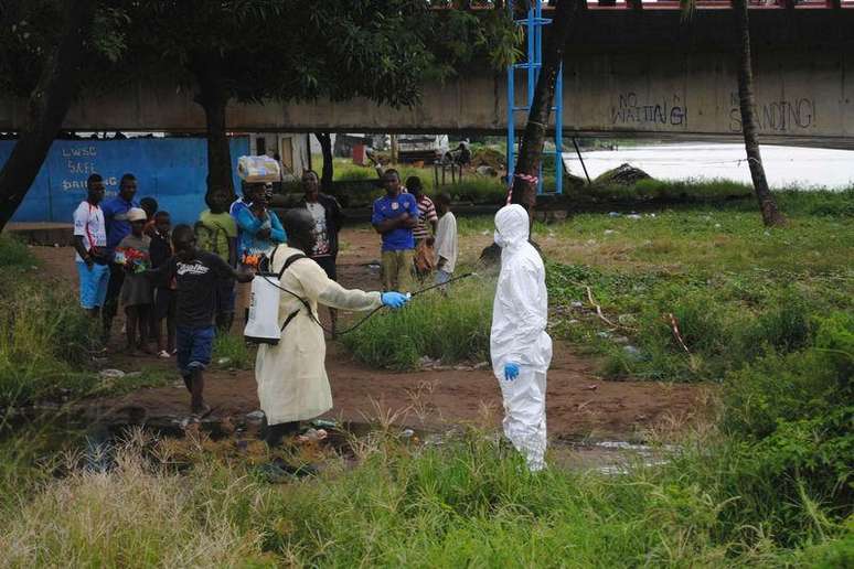 <p>Agente da saúde com vestimenta especial é desinfetado após lidar com um corpo infectado com ebola, em Monróvia, na Libéria</p>